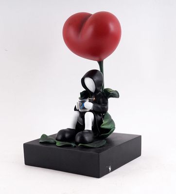 statue d'un chat noir et blanc tenant un ballon rouge en forme de cœur
