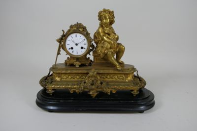 a gold clock sitting on a black base with a cheren