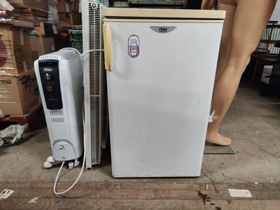 a white refrigerator sitting next to a fan on the floor