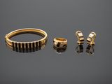 two gold rings and a pair of earrings on a reflective surface