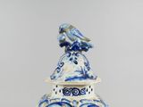 a blue and white vase with a bird on top