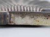 a close up of a silver plate with a knife in it