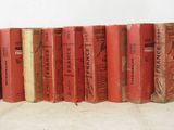 several old books are lined up in a row on a white surface