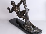 a bronze statue of a man on a rock with his hands in the air
