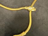 a gold snake necklace on a black surface