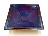 plat carré en verre violet et bleu posé sur un fond blanc