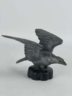 statue représentant un oiseau en plein vol, posée sur un socle en marbre, sur fond blanc