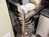 a metal shelf with pots and pans on it in a kitchen
