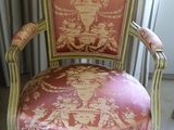 a chair that has a pink and gold upholstered back