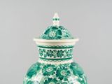 a green and white vase with a lid sitting on a table