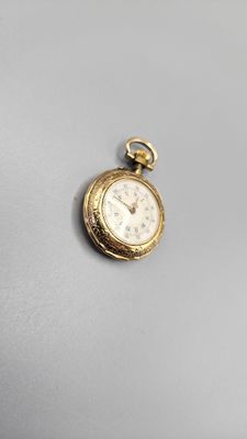 an image of a small gold pocket watch on a white surface