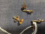 un gros plan sur une paire de boucles d'oreilles en or posées sur un morceau de tissu
