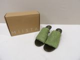 Les chaussons verts se trouvent à côté d'une boîte en carton posée sur une table.