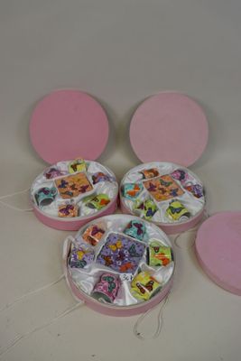 trois boîtes roses contenant des photos, posées sur une table