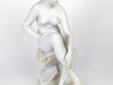 statue blanche représentant une femme assise sur un rocher, les mains posées sur les genoux