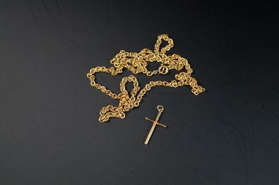 un chapelet et une croix sur une surface noire, avec un fond noir