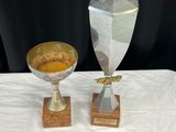 deux trophées posés sur une table blanche, sur fond noir