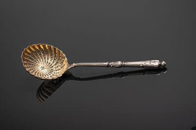 an antique silver spoon with a green stone in the center