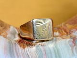 a gold signet ring sitting on top of a piece of marble