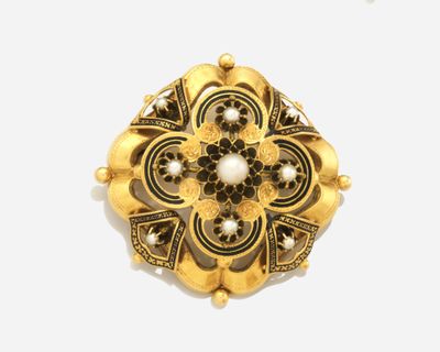 un gros plan d'une broche en or ornée de perles