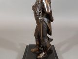 bronze statue of a man with a hat on a black base