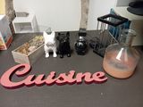 une table sur laquelle se trouvent un vase, une bouteille et une figurine de chat