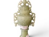 un vase vert posé sur une surface blanche