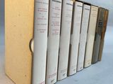 six books are lined up in a row on a white surface