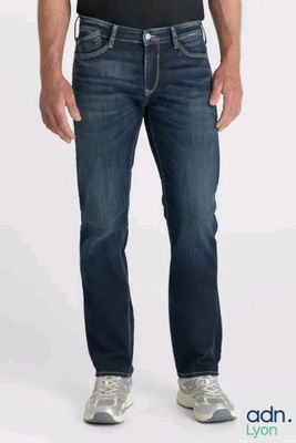 the man is wearing a black shirt and jeans and is posing for a picture
