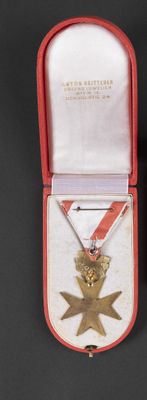 a gold medal in a red case on a black surface