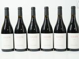 six bouteilles de vin rouge sont alignées sur une surface blanche