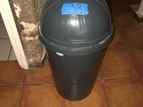 une poubelle noire sur laquelle est collé un autocollant bleu
