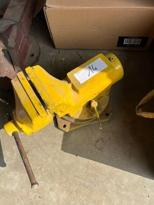 un étau jaune posé par terre à côté d'une boîte