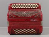 an old red accordion sitting on top of a white table