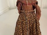 an old fashioned doll with a brown dress and a brown hat