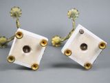 pair of white and gold plated candlesticks with a face in the center