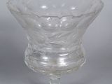 a glass bowl on a stand on a white surface