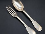 two silver spoons and a fork on a black surface