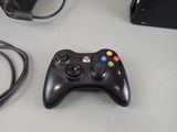 a black game controller sitting on a table next to a computer monitor