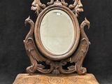 un miroir ancien en bois posé sur un pied, sur fond noir