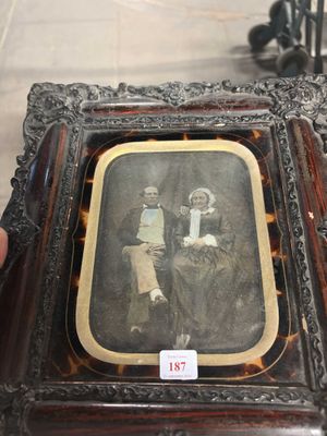 Quelqu'un tient une photo encadrée représentant un homme et une femme.