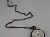 une petite montre de poche attachée à une chaîne, posée sur une table