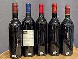 six bottles of red wine are lined up on a wooden table