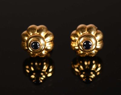 une paire de boucles d'oreilles en or ornées de saphirs sur un fond noir
