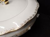 a white bowl with gold trim and a gold ring on it