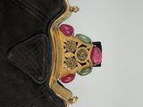 a black purse with a gold handle and a pink and green bead