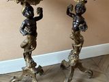 pair of antique bronze statues of cherensils on pedestals on wooden floor