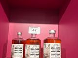 trois bouteilles de whisky sont posées sur une étagère, dans une boîte rose