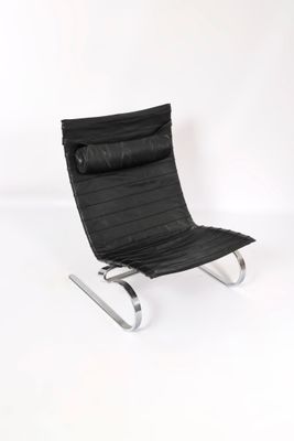 fauteuil en cuir noir avec des pieds chromés sur fond blanc