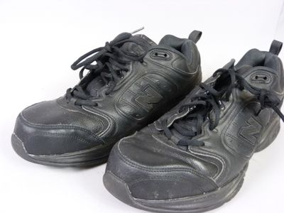 une paire de chaussures noires à lacets posée sur une surface blanche